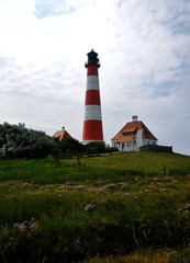 Fototapeta na wymiar Westerhever lighthouse from a distance over green meadows