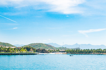 landscape, view from the sea, white beach, palm trees, mountains, boat, plane in the sky, Vietnam. five star hotel.