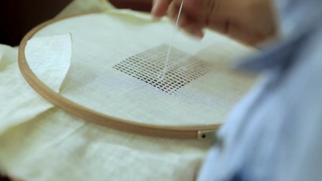 Woman embroiders with a needle and thread