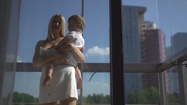 Beautiful young blonde mom playing with her baby boy son - Family values goal - Caucasian mother and child at home - Smooth cinematic handheld movement