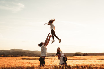 Fototapeta na wymiar Father throws his little girl in the air. Happy family in the countryside having fun