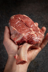 raw tomahawk steak on dark background with spices for grilling