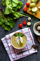 Healthy zucchini cream soup served with poached egg and greens. Proper nutrition food