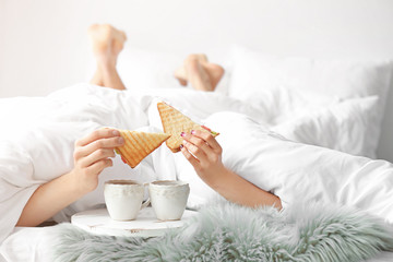 Cute young couple having breakfast in bed