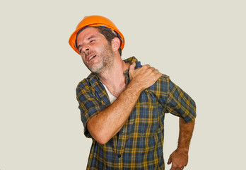 upset and exhausted construction worker or repair man wearing builder helmet complaining suffering pain in his shoulder after working hard