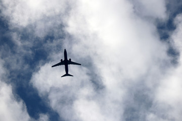 Airplane flying in the sky on background of clouds. Silhouette of a commercial plane, turbulence concept