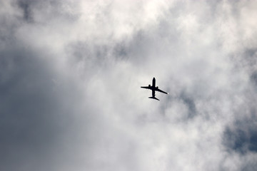 Airplane flying in the sky on background of storm clouds. Silhouette of a commercial plane, turbulence concept