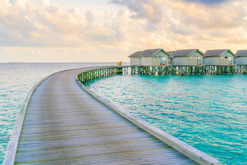 Beautiful water villas in tropical Maldives island at the sunset time .