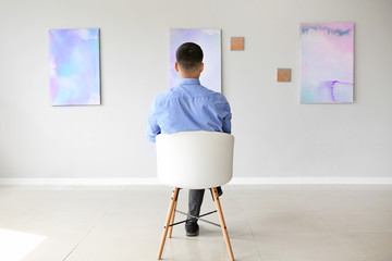 Man sitting on chair at exhibition in modern art gallery