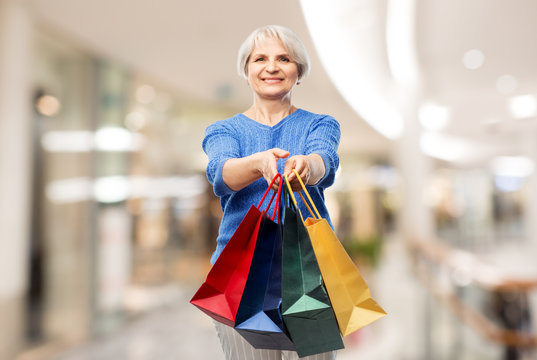 sale and old people concept - smiling senior woman with shopping bags over mall background