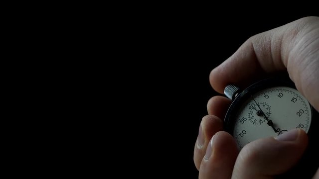 Analogue Stopwatch in Hand on the Black Background. Time Start with Old Chronometer. Man Presses Start Button in the Sport Concept
