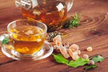 glass teapot with cup of black tea on wooden table