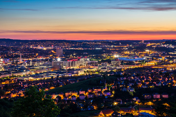 Fototapeta na wymiar Germany, Illuminated skyline of downtown stuttgart city houses and streets and arena of bad canstatt from above after sunset