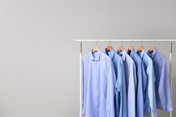 Rack with clothes after dry-cleaning on light background