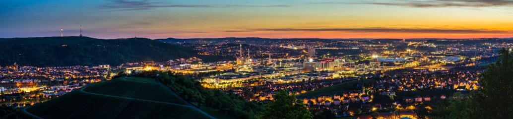 Fototapeta na wymiar Germany, XXL panorama of magic illuminated skyline of downtown stuttgart city houses and arena after sunset from above