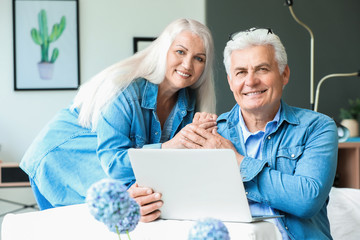 Portrait of happy mature couple with laptop at home