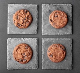 Slate plates and tasty chocolate cookies on dark background