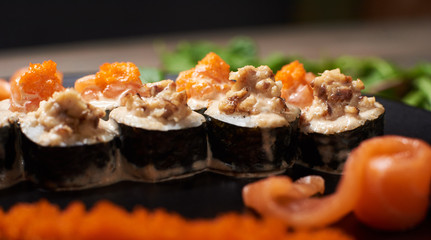 Close up of tasty fresh sushi rolls with fish and rice on black plate. Sushi rolls served on a wooden table in a restaurant