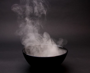 Bowl of hot soup on black background 