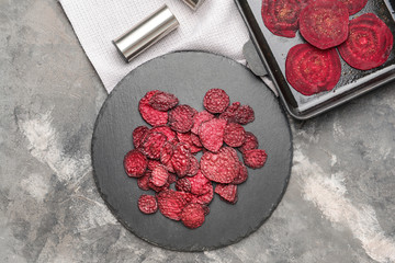 Slate plate with tasty beet chips on table