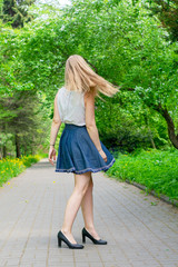 Young woman spinning in the park. The girl in the blue skirt is dancing on the street