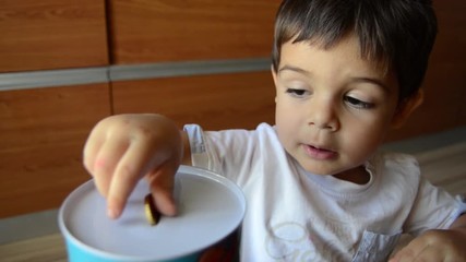 cute two years old saving money, putting coins in metal bank