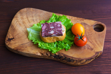 Sandwich with black pudding with a leaf of lettuce and yellow and red tomatoes are on the olive...