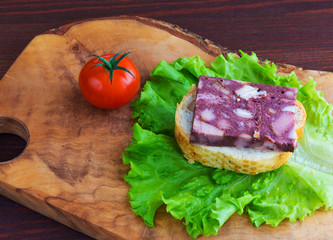 Sandwich with black pudding with a leaf of lettuce and yellow and red tomatoes are on the olive...