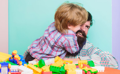 Child care concept. Happy family. Child development and upbringing. Father and son have fun. Bearded hipster and boy play together. Dad and child build plastic blocks. Importance of playing together