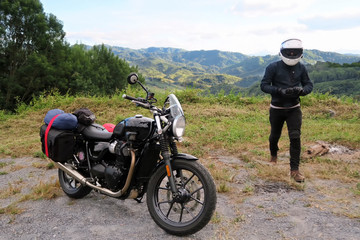 Fototapeta na wymiar Biker walking to classic modern style motorcycle with mountain view landscape. Traveller and adventure outdoor by motorcycle concept. Biker happy in freedom lifestyle travel by motorbike.