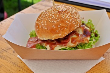 Close up of a big hamburger on the wooden table.