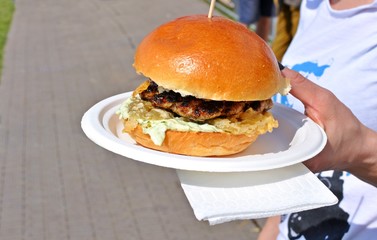 White woman with a big burger in her hand at burger festival.