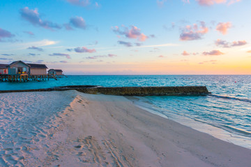 Beautiful sunset with  water villas  in tropical Maldives island .