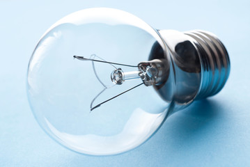 Traditional light bulb. Transparent glass light bulb on blue background.