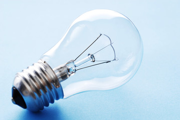 Traditional light bulb. Transparent glass light bulb on blue background.