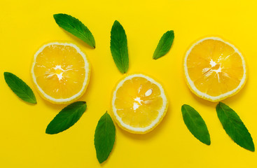 Fototapeta na wymiar Sliced ​​lemon and mint leaves on a bright yellow background. Background for the design of banners, websites, blogs.
