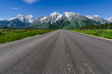 Fototapeta premium Straight road to the Grand teton mountain range. Composite image.