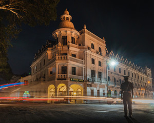 Fototapeta na wymiar kandy sri lanka queen's hotel at night with traffic light trails and a police man