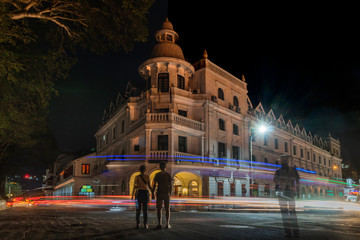 Fototapeta na wymiar kandy sri lanka queen's hotel at night with traffic light trails and a police man in the middle of the street