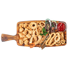 Fried fish, onion rings, batter shrimps, mussels in sauce on a wooden board for serving. Isolate