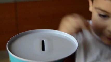 cute two years old saving money, putting coins in metal bank