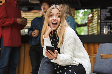 Smiling excited teenager sitting outdoors