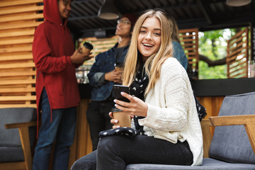 Smiling excited teenager sitting outdoors