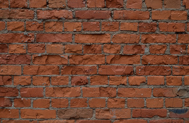The unique texture of the old, partially destroyed brick terracotta wall of the house close up