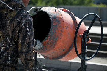 orange concrete mixer prepares cement mortar