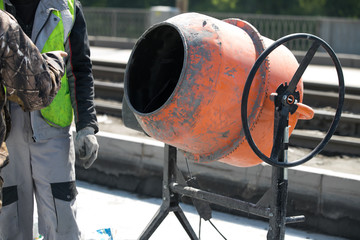 orange concrete mixer prepares cement mortar