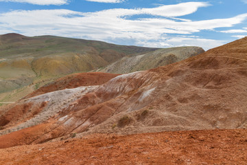 Close up surface of red mountains in Kyzyl-Chin valley in Altay. Scenic landscape with clouds. Summer concept.