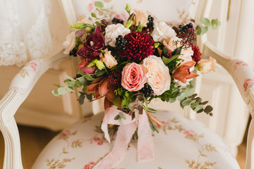 Beautiful modern bridal bouquet of colorful fresh flowers with sikl ribbons. Classic wedding traditional accessory.