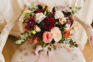 Beautiful modern bridal bouquet of colorful fresh flowers with sikl ribbons. Classic wedding traditional accessory.