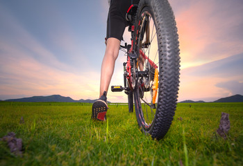 leg of woman cyclist bicycle paused riding on the way of meadow field, adventure woman riding...